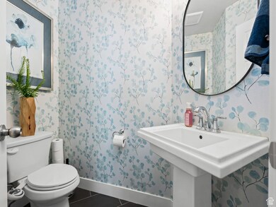Bathroom with wallpapered walls and dark tile patterned floors