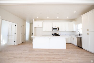Kitchen with tall cabinetry, GE stainless steel appliances, and a view of the French doors to the office space.