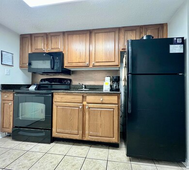 Kitchen with dark countertops, black appliances, l