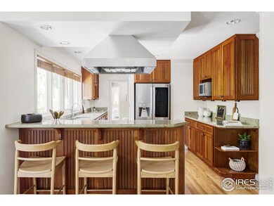 The kitchen itself is a true highlight, outfitted with custom wood cabinetry, stainless steel appliances including a Wolf range and Cove dishwasher, ample counter space, and an eat-in breakfast nook overlooking the deck and gardens.