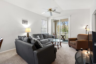 Carpeted living room featuring ceiling fan and vau