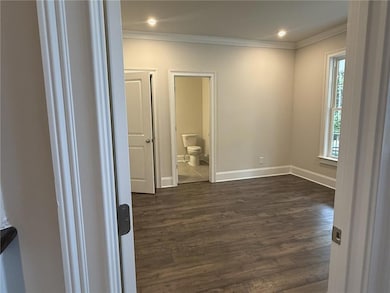Empty room with dark wood-type flooring, ornamental molding, and recessed lighting