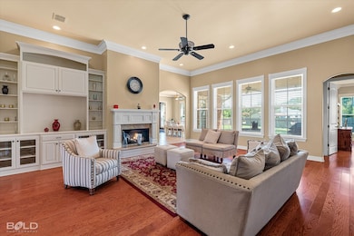 Living room featuring arched walkways, ceiling fan, crown molding, wood finished floors, and a premium fireplace