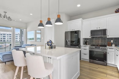 Modern kitchen features sleek white cabinetry, a l