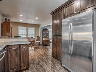 Kitchen featuring stainless steel appliances, recessed lighting, dark wood finished floors, dark brown cabinets, and light stone counters