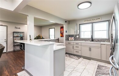 Kitchen with stainless steel refrigerator, light tile flooring, backsplash, gray cabinetry, and sink