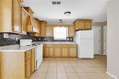 Kitchen with white appliances, backsplash, a sink, light countertops, and light tile patterned floors