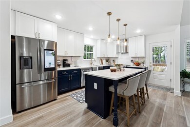 Kitchen featuring appliances with stainless steel finishes, blue cabinets, light wood finished floors, a breakfast bar area, and recessed lighting
