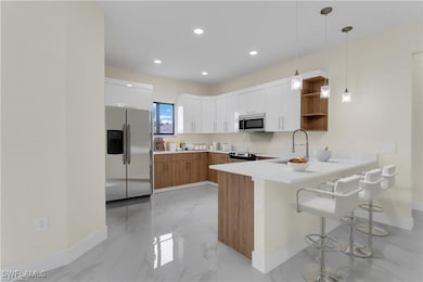 Kitchen with white cabinetry, sink, kitchen penins