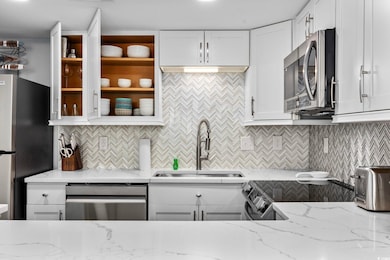 Kitchen featuring backsplash, white cabinetry, and light stone countertops