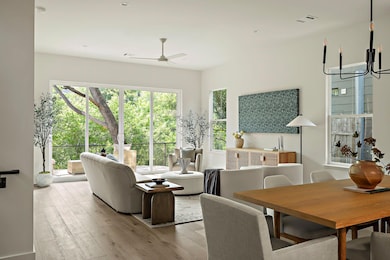 Living area with a ceiling fan, wood finished floors, and a chandelier