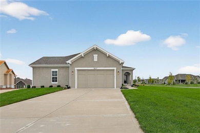 View of front of house featuring stucco siding, a front yard, concrete driveway, and an attached garage
