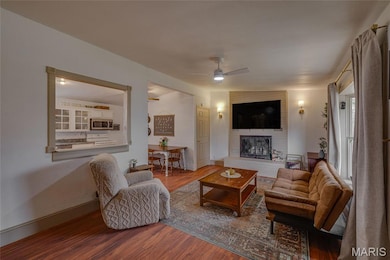 Living area featuring wood finished floors, a fireplace, ceiling fan, and lofted ceiling