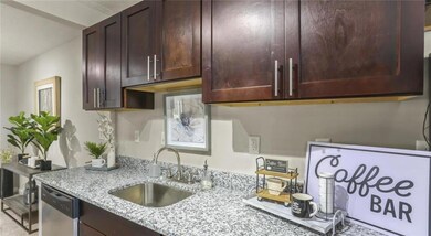 Kitchen with dark brown cabinetry, sink, dishwasher, and light stone counters