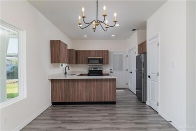 Kitchen with a peninsula, a sink, a chandelier, light countertops, and appliances with stainless steel finishes