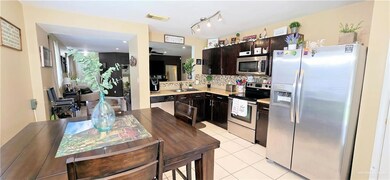 Kitchen featuring appliances with stainless steel finishes, a sink, decorative backsplash, light countertops, and dark brown cabinetry