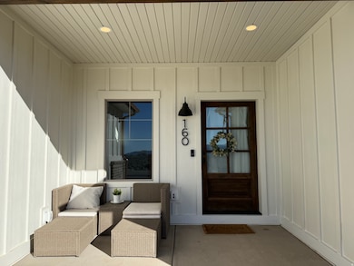Property entrance with covered porch and board and batten siding