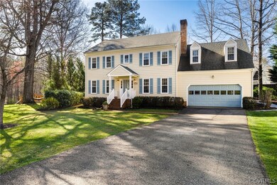 Colonial home featuring a front yard and a garage