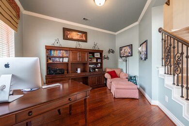 The study has plank hardwood flooring, crown molding and views of the lush front yard.