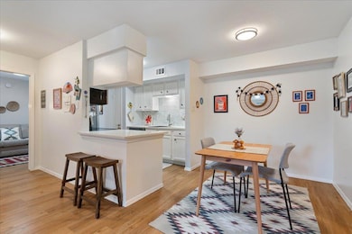 Kitchen featuring light countertops, tasteful backsplash, a kitchen bar, light wood-type flooring, and white cabinetry