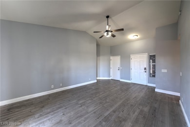 Empty room featuring ceiling fan, dark wood finish