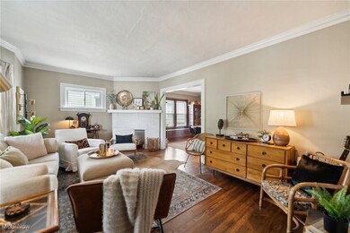 Living room with a fireplace, ornamental molding, and hardwood flooring
