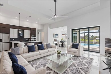 Living room with ceiling fan, light tile patterned flooring, sink, and a high ceiling
