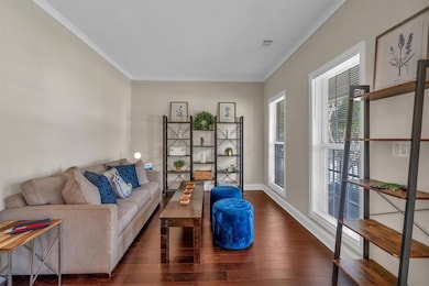 Living area with wood finished floors, ornamental molding, and baseboards