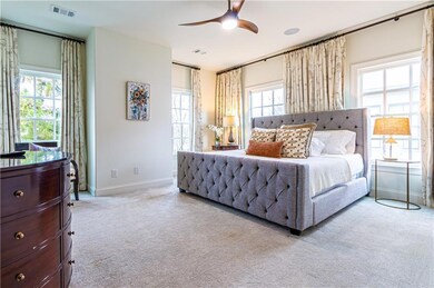 Bedroom featuring light carpet, ceiling fan, and multiple windows