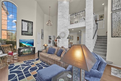 Living area featuring wood finished floors, a towering ceiling, stairs, and a chandelier