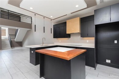 Kitchen with butcher block counters, dark cabinetry, electric cooktop, and recessed lighting