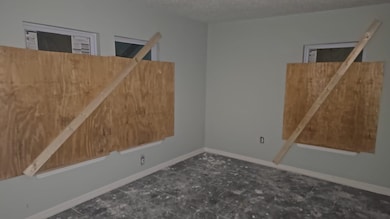 Empty room with a textured ceiling and baseboards