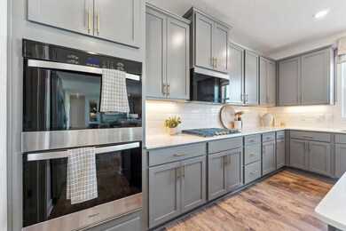 Your kitchen will include our KitchenAid Gourmet appliance package: a 5 burner gas cooktop, wood hood, built in microwave and convection oven, and dishwasher. Tiled backsplash included. Photo of model home, colors and finishes are similar.