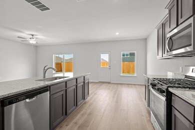 Kitchen with appliances with stainless steel finishes, light stone counters, light wood finished floors, a ceiling fan, and recessed lighting