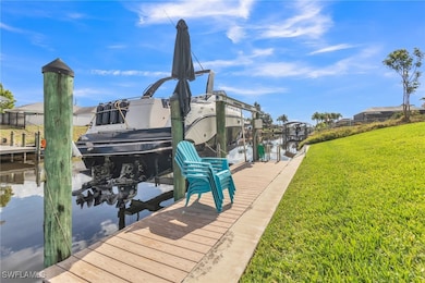 Dock with boat lift, a lawn, and a water view