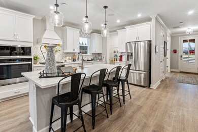 Chef's kitchen including built in double wall ovens, quartz, SS appliances, and ceramic tile backsplash.