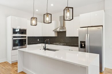 Kitchen with decorative backsplash, stainless steel appliances, light wood-style floors, white cabinetry, and modern cabinets