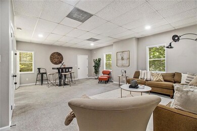 Living area featuring carpet, baseboards, and a drop ceiling