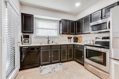 Kitchen with dark brown cabinets, light tile patte