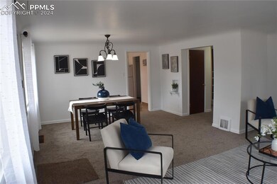 Carpeted dining area featuring a notable chandelie