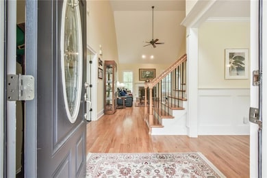 Entrance foyer with stairs, light wood-type flooring, ceiling fan, ornamental molding, and a wainscoted wall