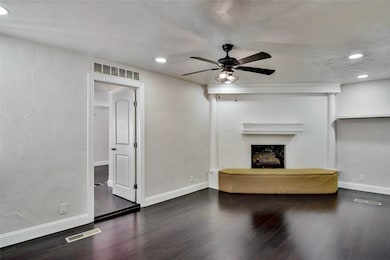 Unfurnished living room with a textured wall, dark wood-style flooring, a fireplace, ceiling fan, and recessed lighting