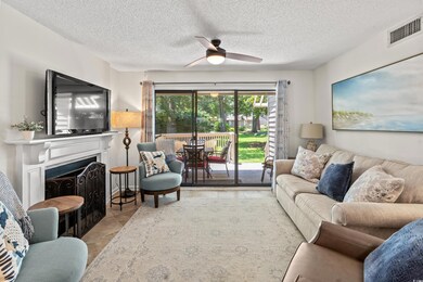 Living area with a ceiling fan, tile patterned flooring, a textured ceiling, and a fireplace with flush hearth