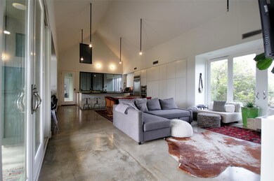Living room featuring high vaulted ceiling, concr