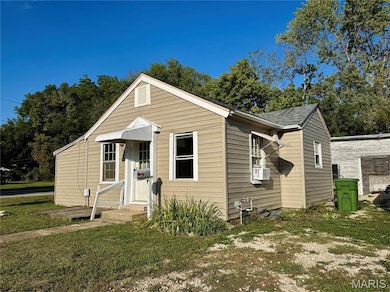 Bungalow-style home featuring a front yard and view of wooded area