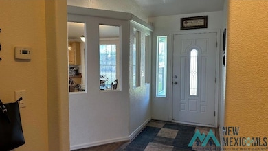 Entryway with a textured wall and baseboards