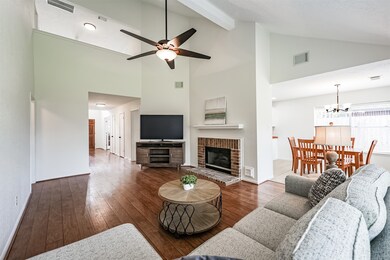 Continue straight ahead from the foyer into the heart of this home where you'll find an inviting family room with a soaring two-story beamed ceiling, a lighted ceiling fan, wood-look laminate floors, and a gas log fireplace with a brick surround.