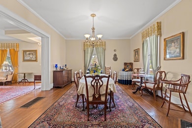 Dining room with a chandelier, healthy amount of natural light, wood finished floors, and ornamental molding