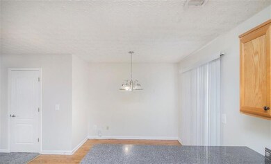 Unfurnished dining area featuring a chandelier, a textured ceiling, baseboards, and light wood-style floors