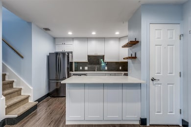 Kitchen featuring a peninsula, open shelves, white cabinetry, freestanding refrigerator, and tasteful backsplash